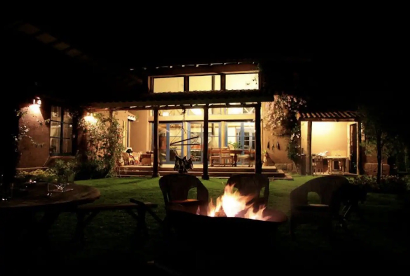 The main house at Melissa Wasi lit up at night, with a fire pit on the lawn