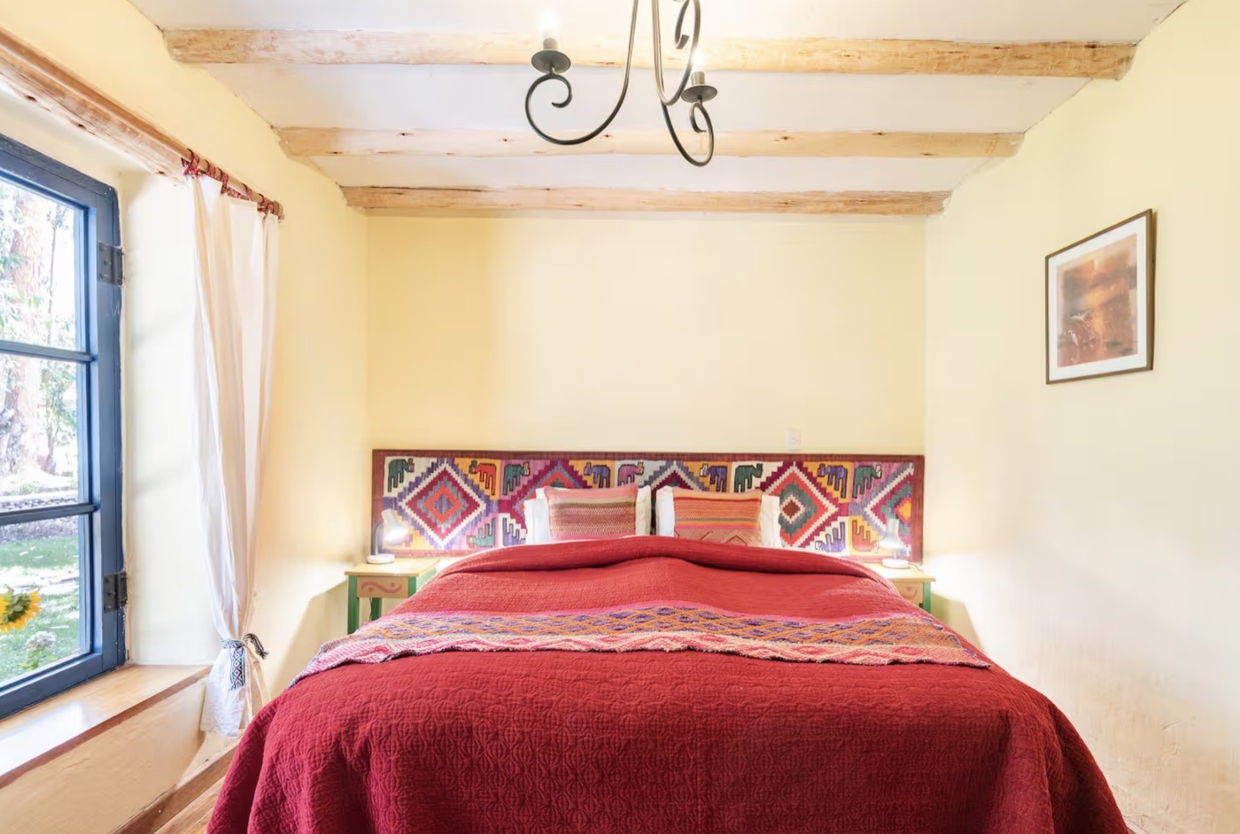 A double room with a red bedspread and Andean textile headboard